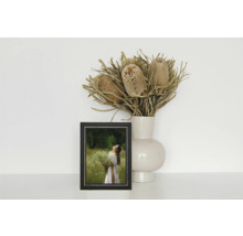 Nature morte décorative avec une photo dans un cadre, un vase et des fleurs séchées