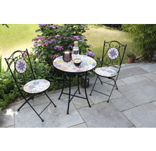 Gartenszene mit einem kleinen Tisch und zwei Stühlen mit Mosaikmuster auf einer Terrasse.