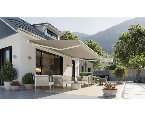 Façade de maison avec store banne déployé et mobilier de jardin sur la terrasse.