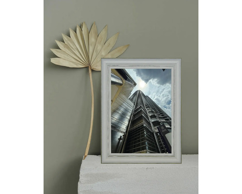Dekorative Szene mit einem gerahmten Foto eines hohen Gebäudes und einer getrockneten Palme