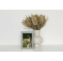 Dekoratives Stillleben mit Blumen in einer Vase und einem gerahmten Bild