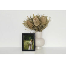 Cadre photo décoratif à côté d'un vase avec des fleurs séchées