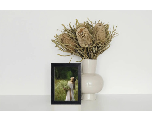 Cadre photo décoratif à côté d'un vase avec des fleurs séchées