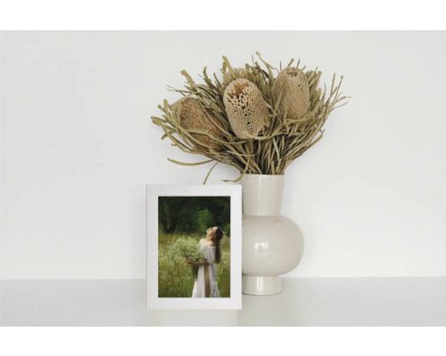 Nature morte décorative avec un cadre photo, un vase et une composition de fleurs séchées