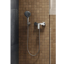 Brausegarnitur mit Handbrause und Armatur vor gefliester Wand
