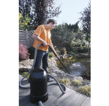 Un homme nettoie un bassin de jardin avec un aspirateur de bassin.