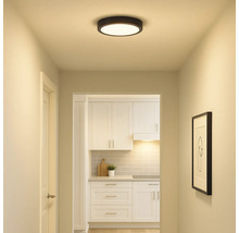 Flur mit runder Deckenleuchte und Blick in eine Küche mit weissen Möbeln