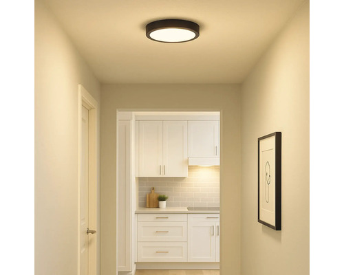 Flur mit runder Deckenleuchte und Blick in eine Küche mit weissen Möbeln