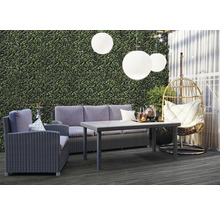 Gartenlounge-Set mit Sofa, Sessel, Tisch und Hängekorb auf einer Terrasse mit Hintergrund einer Pflanzenwand