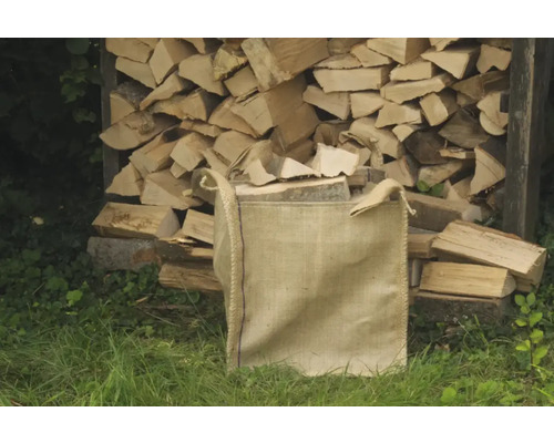 Sac de bois de chauffage devant une pile de bois