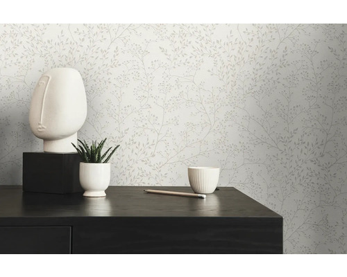 Scène avec papier peint à motifs floraux, une sculpture de visage blanche, une plante succulente en pot et un crayon sur une table foncée.