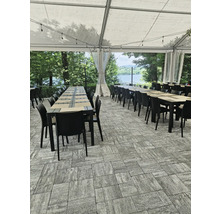 Une terrasse couverte avec des tables et des chaises sur des pavés.