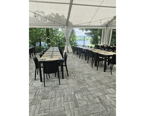 Une terrasse couverte avec des tables et des chaises sur des pavés.