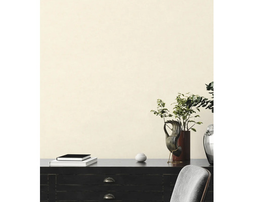 Intérieur décoratif avec commode, livres, plantes et sculptures devant un mur