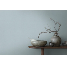 Bol décoratif, vase et branches sur une table en bois devant un mur