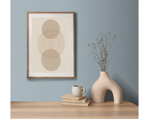 Nature morte décorative avec une reproduction d'art encadrée, des livres, une tasse et un vase sur une table