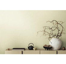 Scène décorative avec théière, livre et branches dans un vase sur un buffet