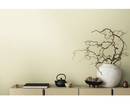 Scène décorative avec théière, livre et branches dans un vase sur un buffet