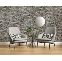 Wohnraum mit zwei Sesseln, Kissen, Beistelltisch, Spiegel und einer Wandtapete im Steinmuster