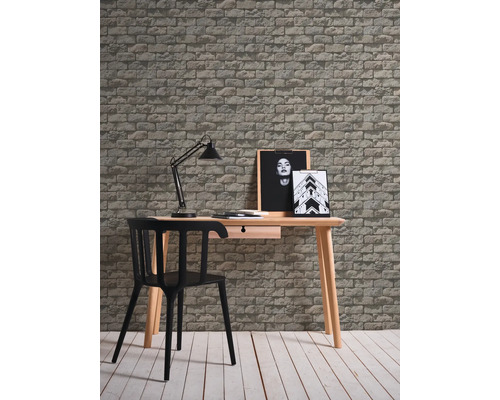 Bureau avec bureau, chaise, lampe de bureau et papier peint à motif de briques pour une atmosphère productive.