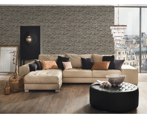 Salon avec canapé d'angle, ottoman, décoration et papier peint imitation pierre