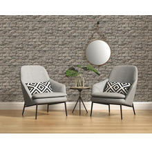 Deux fauteuils gris avec coussins devant un mur de briques et un miroir rond