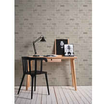 Bureau avec table, chaise, lampe et papier peint à motif de briques.