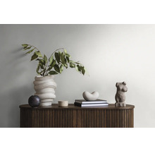 Intérieur décoratif avec un buffet en bois élégant, un vase avec des plantes, une sculpture et des livres pour une ambiance élégante dans la pièce.