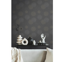 Salon décoratif avec papier peint à motifs, canapé et divers vases sur une table noire