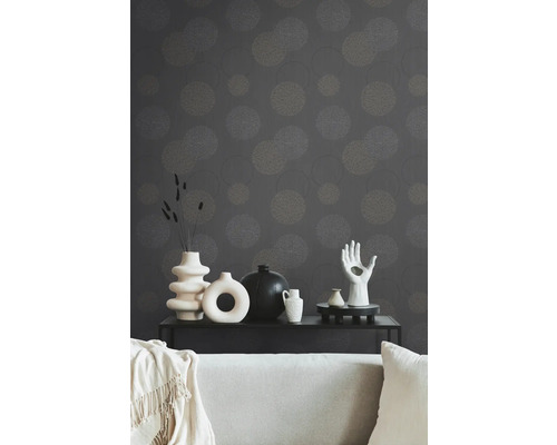 Salon décoratif avec papier peint à motifs, canapé et divers vases sur une table noire