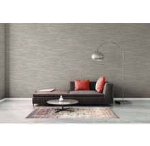 Salon avec canapé, tapis, table et lampadaire devant un papier peint structuré.