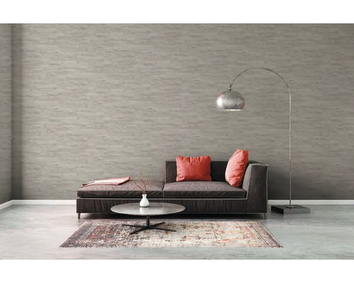 Salon avec canapé, tapis, table et lampadaire devant un papier peint structuré.