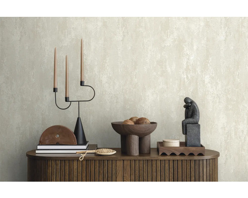 Arrangement décoratif sur une commode devant un papier peint structuré.