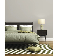 Schlafzimmer mit Bett, Nachttisch, Lampe und Teppich