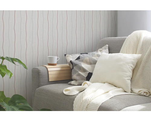 Wohnzimmer mit gemusterter Tapete, Sofa, Kissen und Beistelltisch