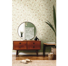 Wohnzimmer mit Blumentapete, Kommode, Spiegel und Dekorationen.