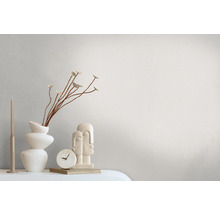 Arrangement décoratif avec vase, horloge, bougie et sculpture sur une surface.