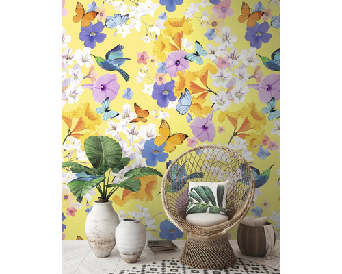 Intérieur décoratif avec papier peint jaune, orné de fleurs, de papillons et d'oiseaux, complété par un fauteuil en rotin et des plantes d'intérieur