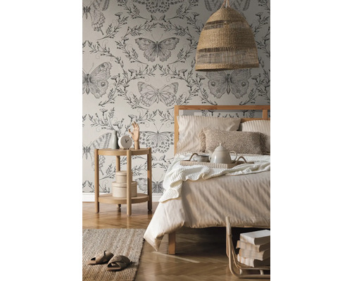 Chambre avec lit, table de chevet, lampe et papier peint à motifs de papillons