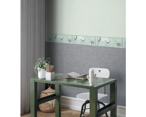 Chambre d'enfant décorative avec bureau, chaise et bordure de papier peint sur le thème de la forêt.
