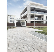 Photo extérieure d'un immeuble d'habitation moderne avec allée pavée et éléments décoratifs.