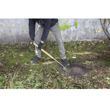 Une personne creuse un trou dans le jardin avec une bêche.