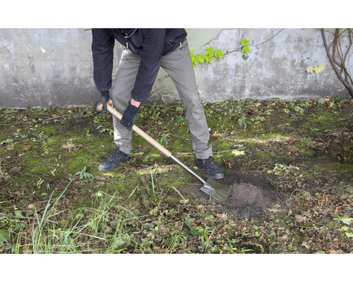 Une personne creuse un trou dans le jardin avec une bêche.