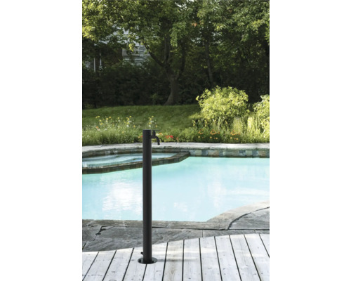 Douche de jardin à côté de la piscine avec terrasse en bois et environnement verdoyant en arrière-plan.