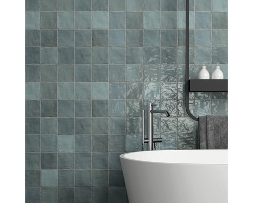 Modernes Badezimmer mit bläulichen Wandfliesen, Badewanne und Armatur.