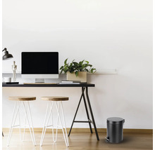 Arbeitszimmer mit Schreibtisch, Stühlen und einem runden Treteimer.