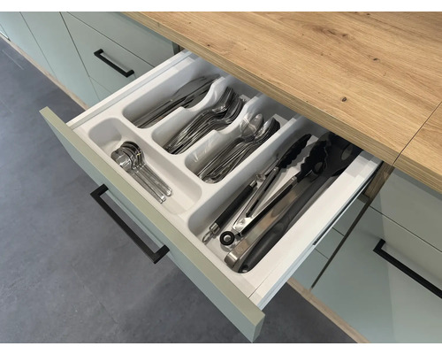 Geöffnete Küchenschublade mit Besteckeinsatz und verschiedenen Besteckteilen.