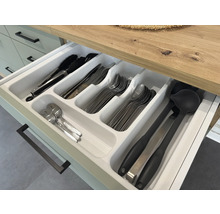 Geöffnete Schublade mit Besteckkasten und verschiedenen Küchenutensilien wie Zange, Messern, Gabeln, Löffeln und Schöpfkellen.