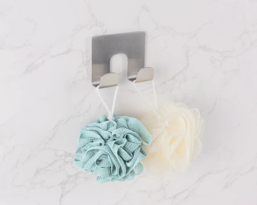 Draufsicht auf einen Handtuchhaken aus Edelstahl mit Badeschwämmen an einer Marmorwand