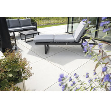 Terrasse avec mobilier de jardin composé d'un canapé, d'une table et d'un transat avec coussins.